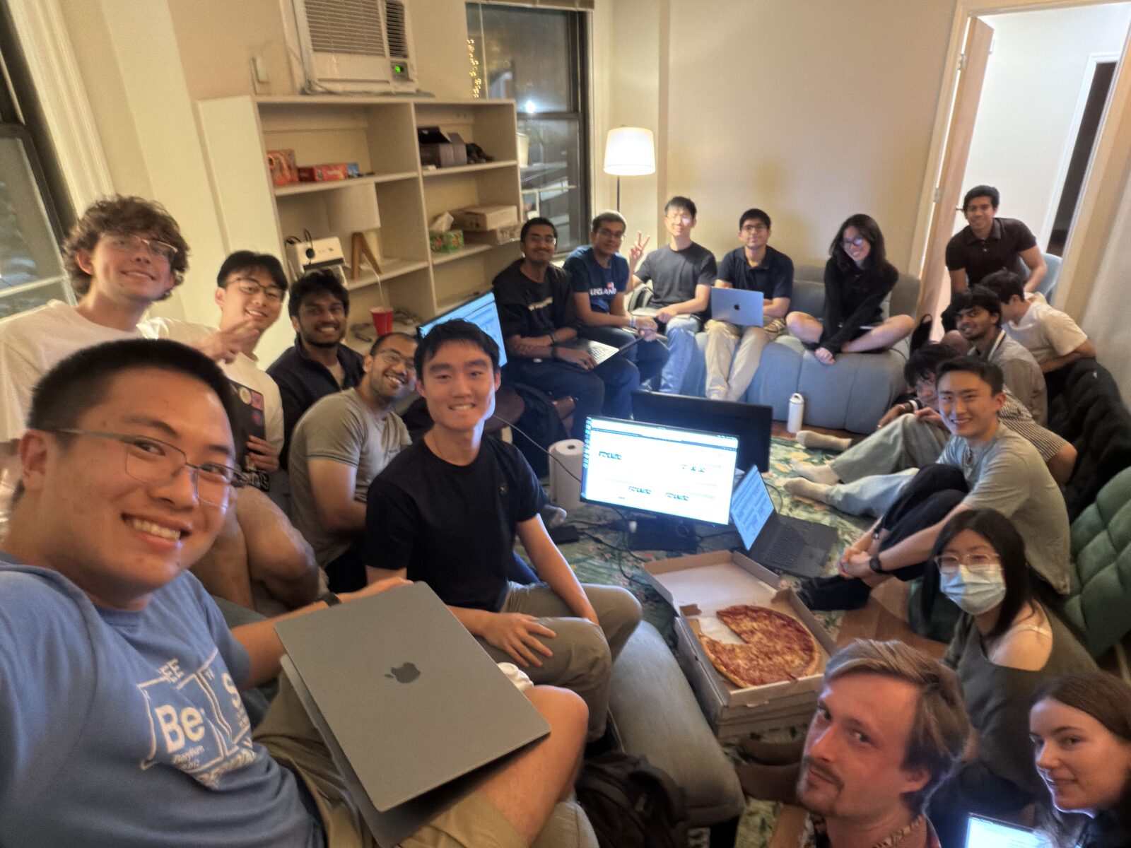 MLn Reading Club, Week 16 — the group on the couches and floor at CASI, laptops open, a monitor on the rug and a pizza box in the middle