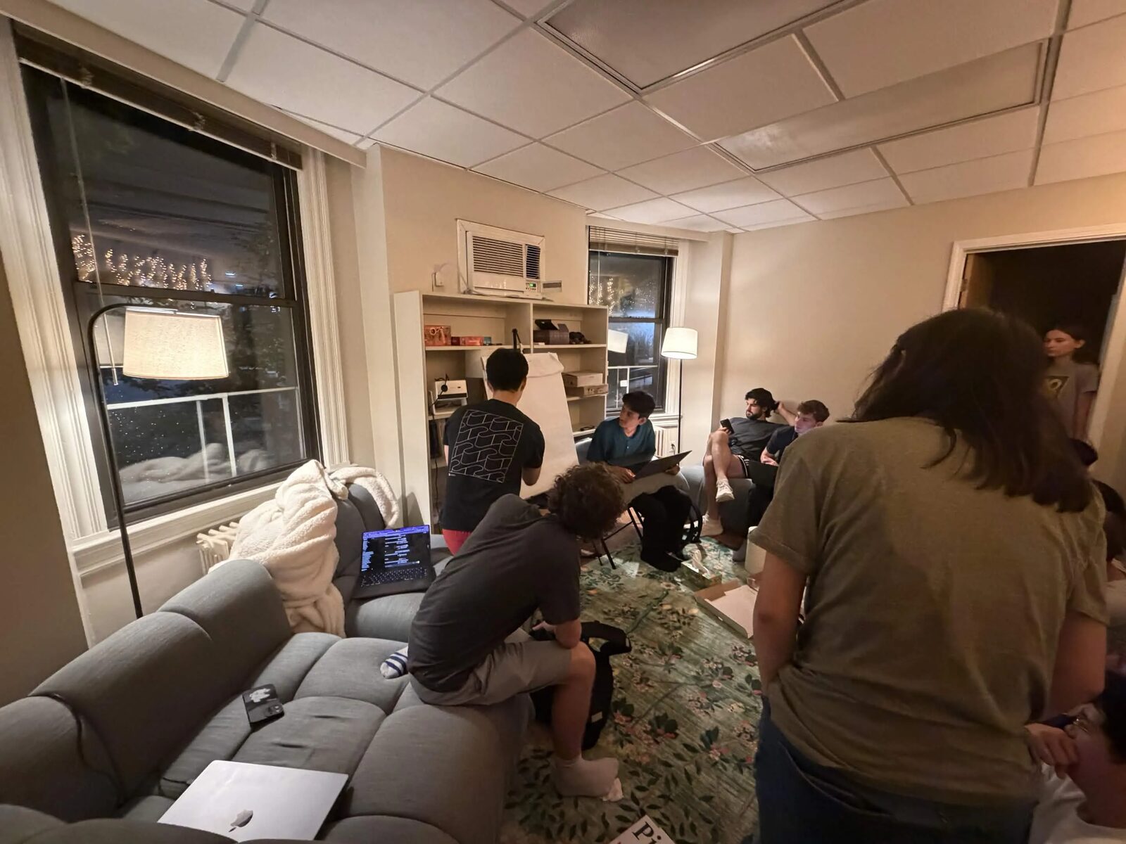 The room from the couch — the flip chart in the corner and the discussion around it